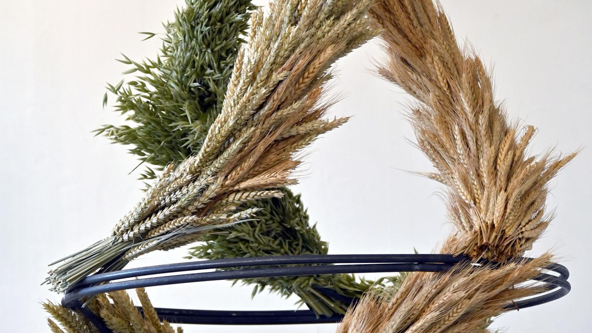 Close up of a sculpture made from three garlands of wheat (brown, yellow, and green) swirling around each other and joining at the top.