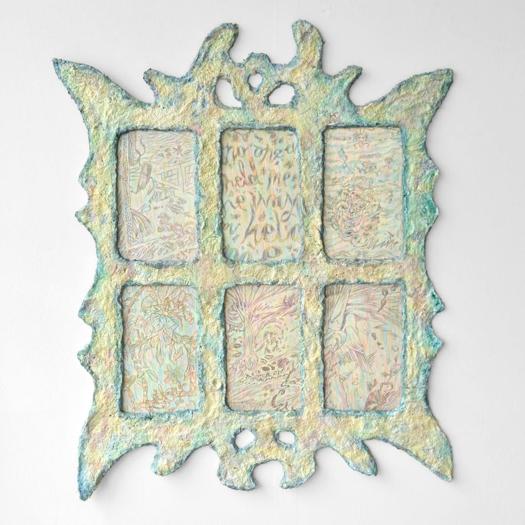 A gothic papier mache window in yellow and blue, with each of its paints featuring a small and heavily detailed Biro drawing.