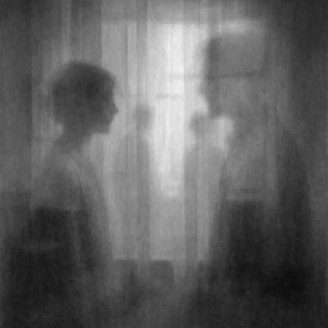 Hazy image by Brian Daines, two blurry people speaking in front of a foggy curtain with shadows in background.