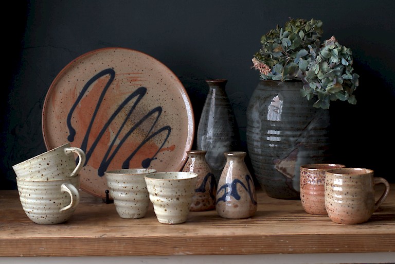 Assortment of ceramic tableware by Burnt Crust Pottery, in a peach, black, and white clays. Some pieces are decorated with black squiggles.