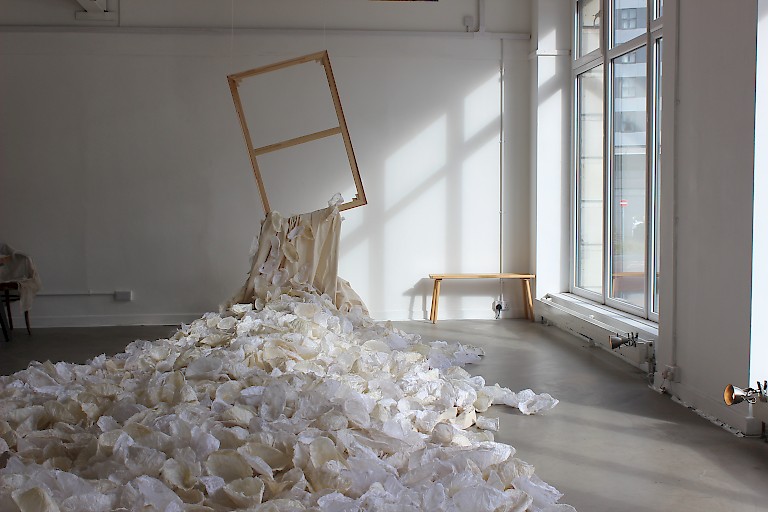 Installation by Cath Acons, a wooden window frame suspended in the air, from which thousands of papier-mache shell forms spill out into the room.