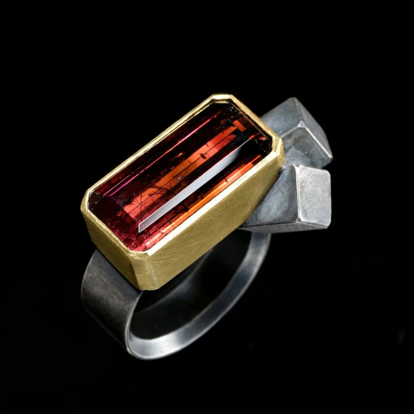 Ring by Chris Boland in silver and gold, featuring a cluster of geometric shapes and a large red rectangular gemstone.
