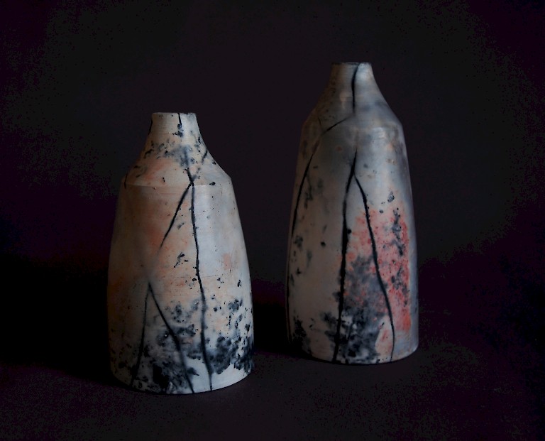Two ceramic vessels by Claire Allam, highly burnished in white, with patches of red and black markings.