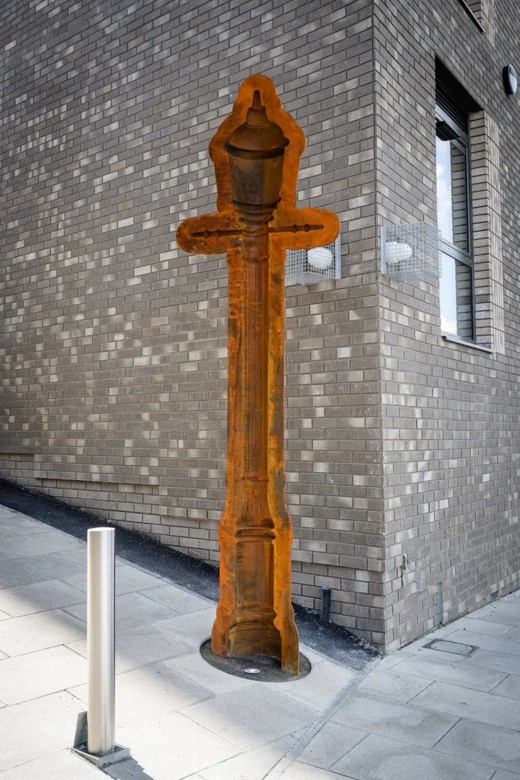Public artwork by David Appleyard, a negative impression of a Victorian street lamp in metal with a rust-coloured oxidised finish.