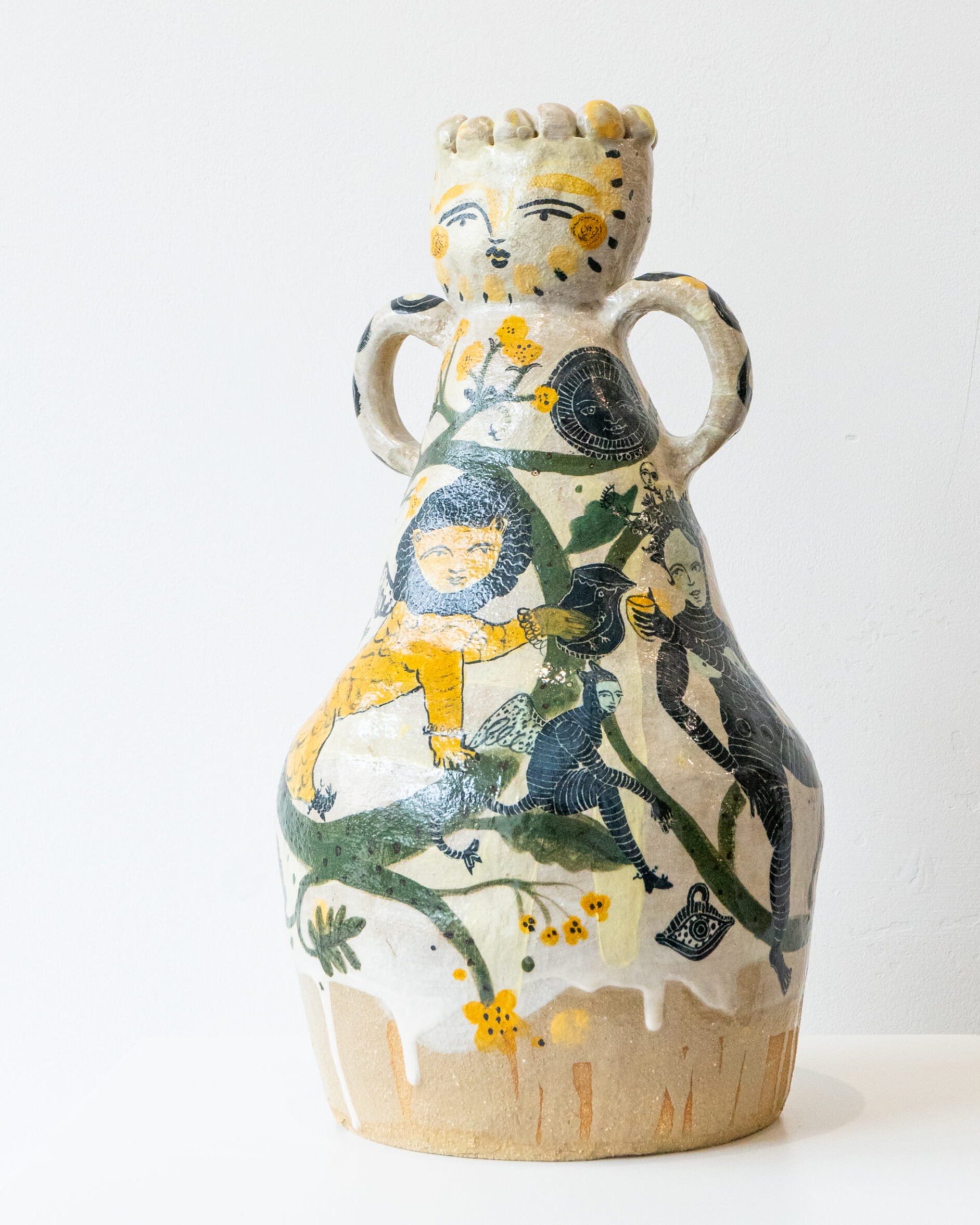 Ceramic vase by Evelyn Albrow, with large handles and a face at the top, handpainted with Medieval imagery of lions and pixies.