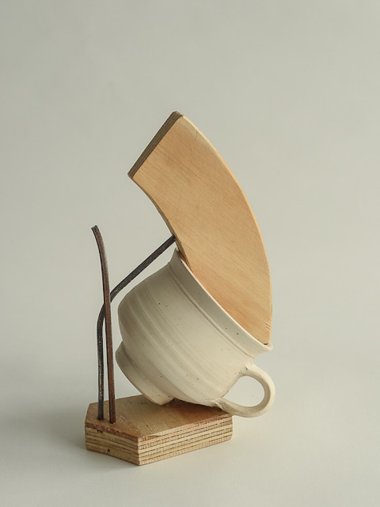 Abstract sculpture by Gillian Brent using wood, metal and a ceramic teacup. Appears precariously balanced or in motion.