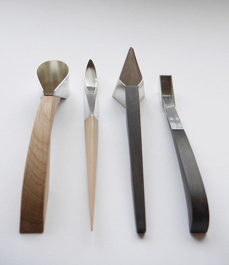 Various spoon-like silver vessels by Imogen Clarkstone, with sleek carved wooden handles.