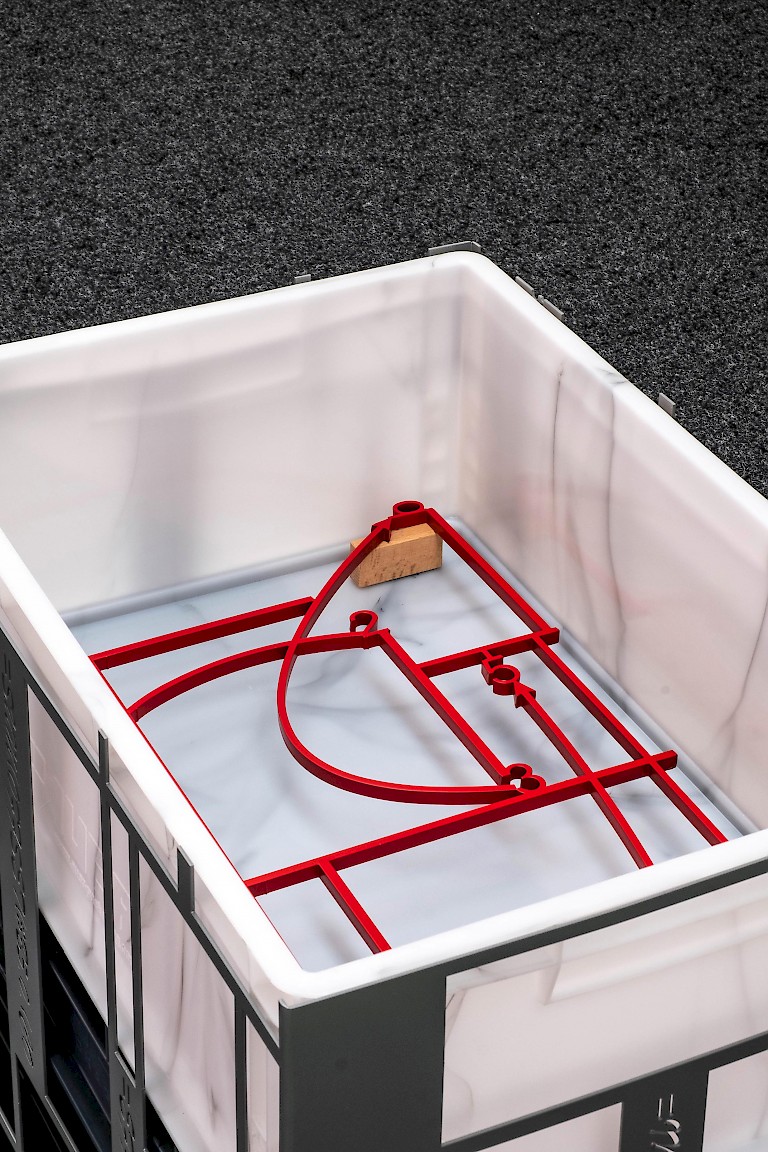 Metal cage-like sculpture by James Clarkson with marble interior, contains 3D red diagram in metal.