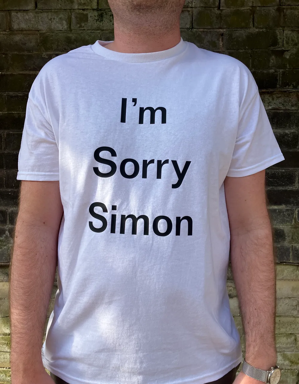 Man wears a white t-shirt with black text that reads "I'm Sorry Simon"; part of conceptual artwork by Jon Cannon.