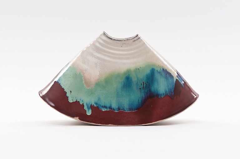 Ceramic vase by Penny Withers, wedge-shaped and with layers of melting colours: white, icy blue, earth red-brown. The colours look like a frosty wooded landscape.