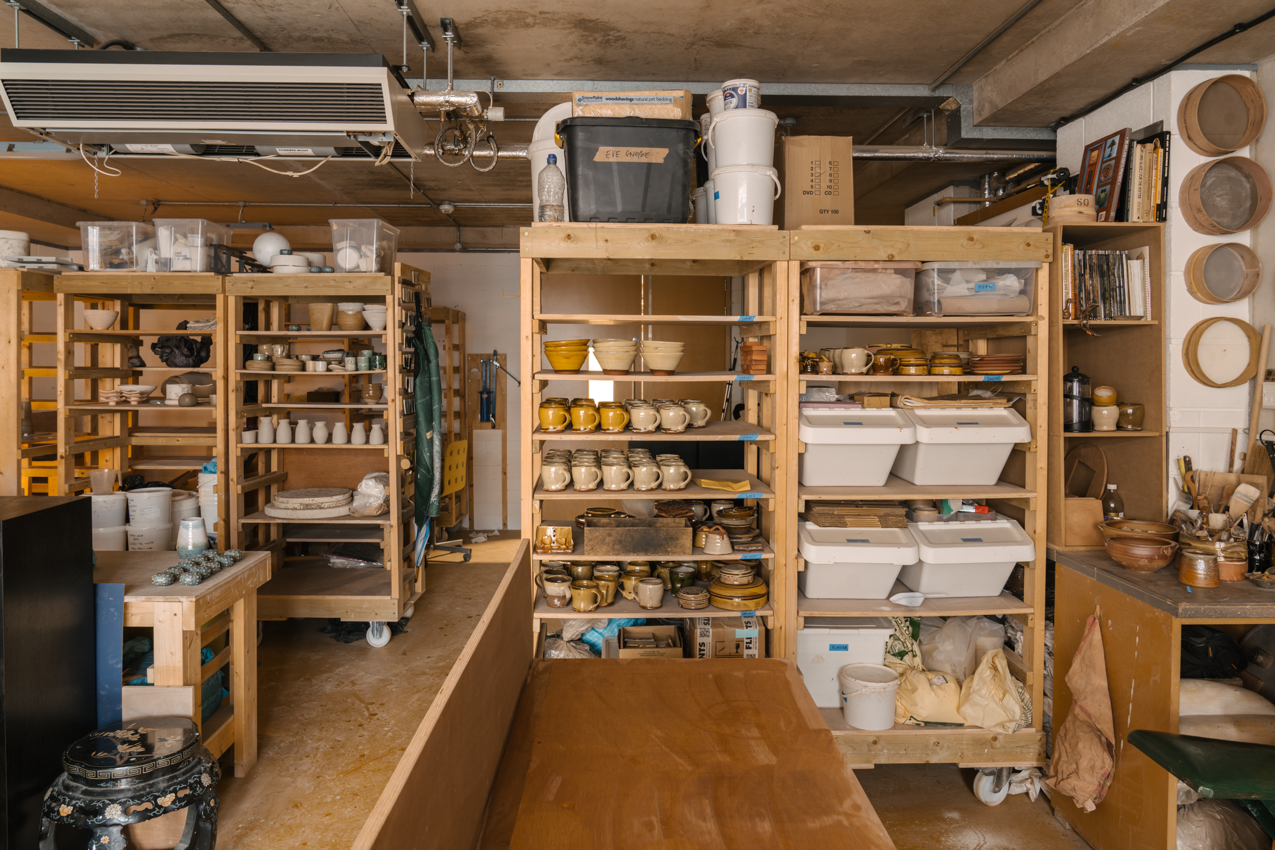 Large studio full of shelves stacked with pottery.